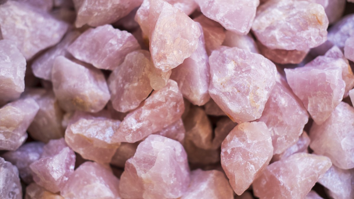 Diversas pedras brutas de quartzo rosa amontoadas juntas.