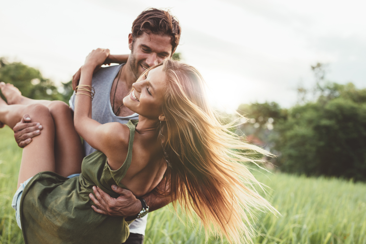 Homem e mulher apaixonados correndo sobre campo verde.