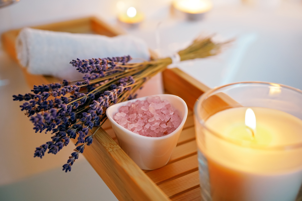 Ervas e sais separados junto a vela acesa e uma toalha, ingredientes utilizados na preparação do banho para dar ânimo.