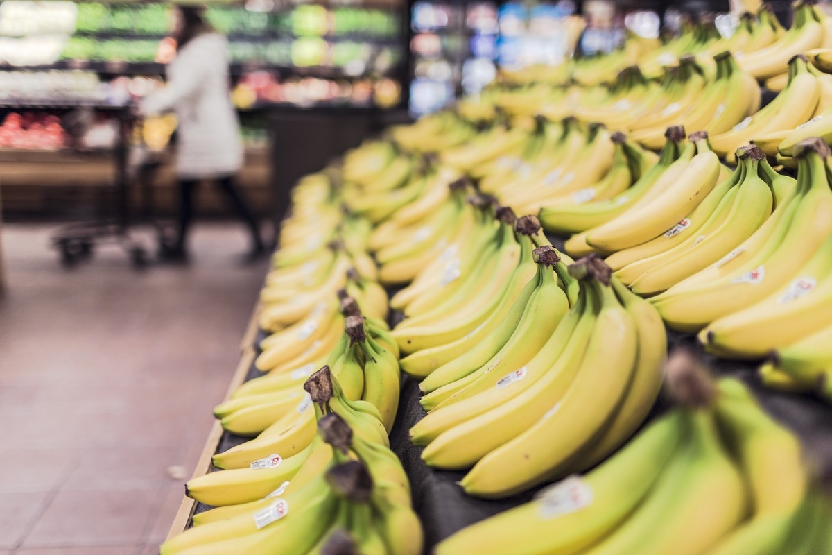 Cachos de banana enfileirados em prateleira de supermercado.