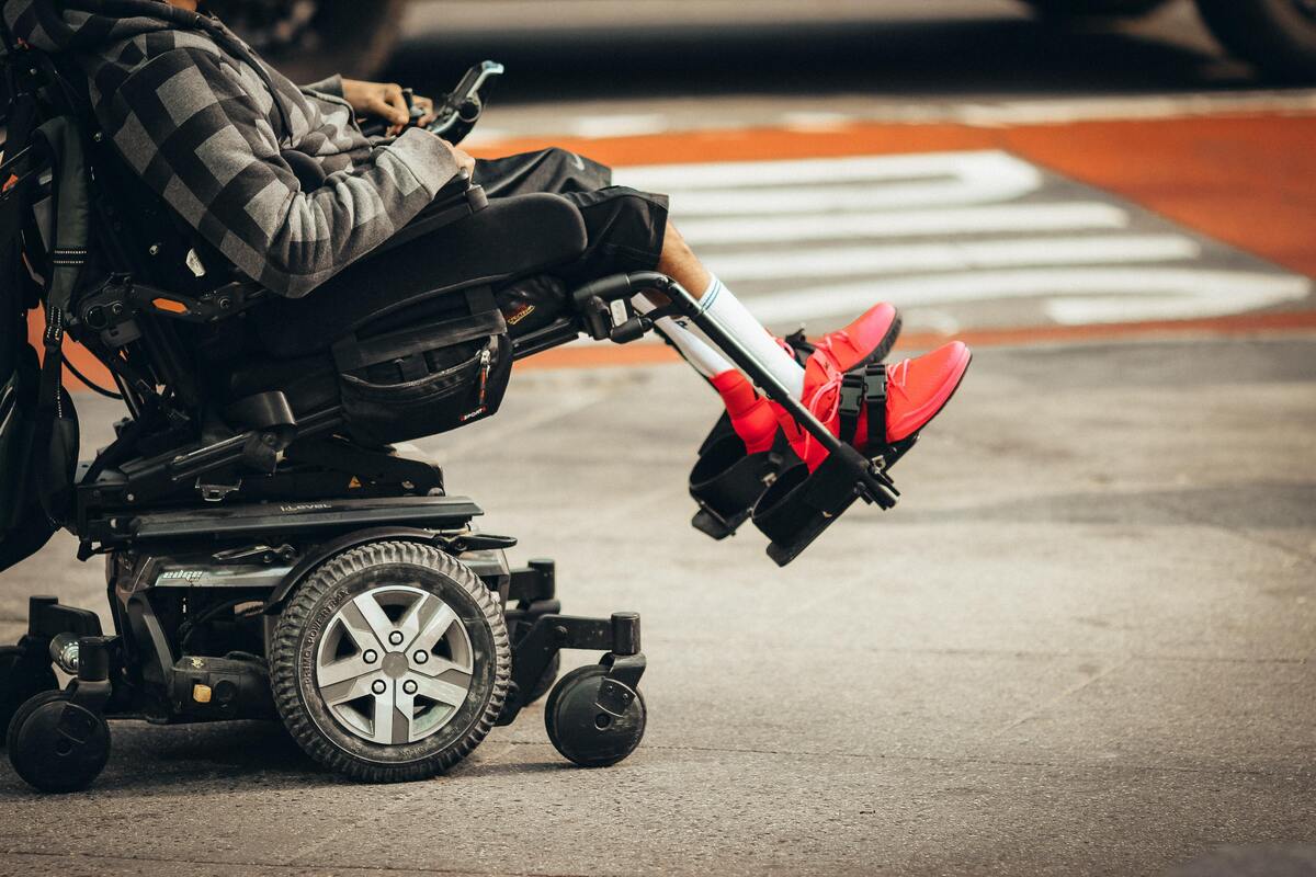 Homem deficiente com deficiência nas pernas andando de cadeira de rodas