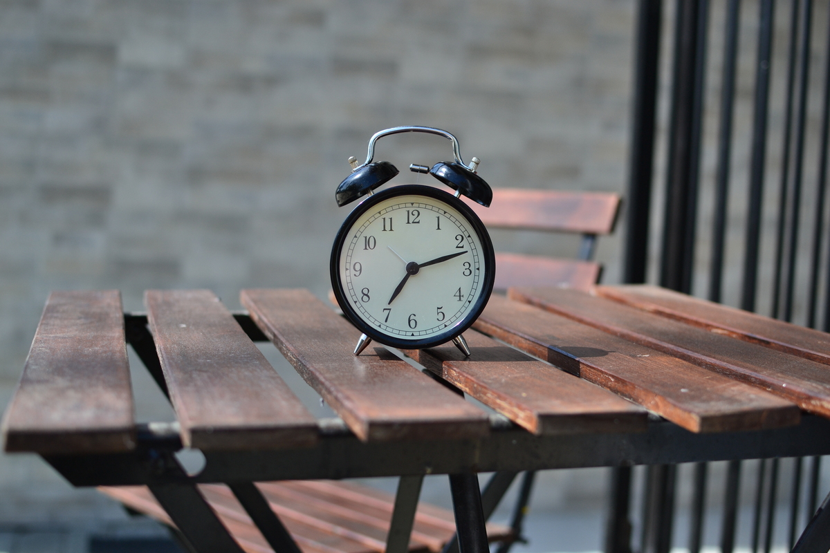 Relógio sobre mesa de madeira.