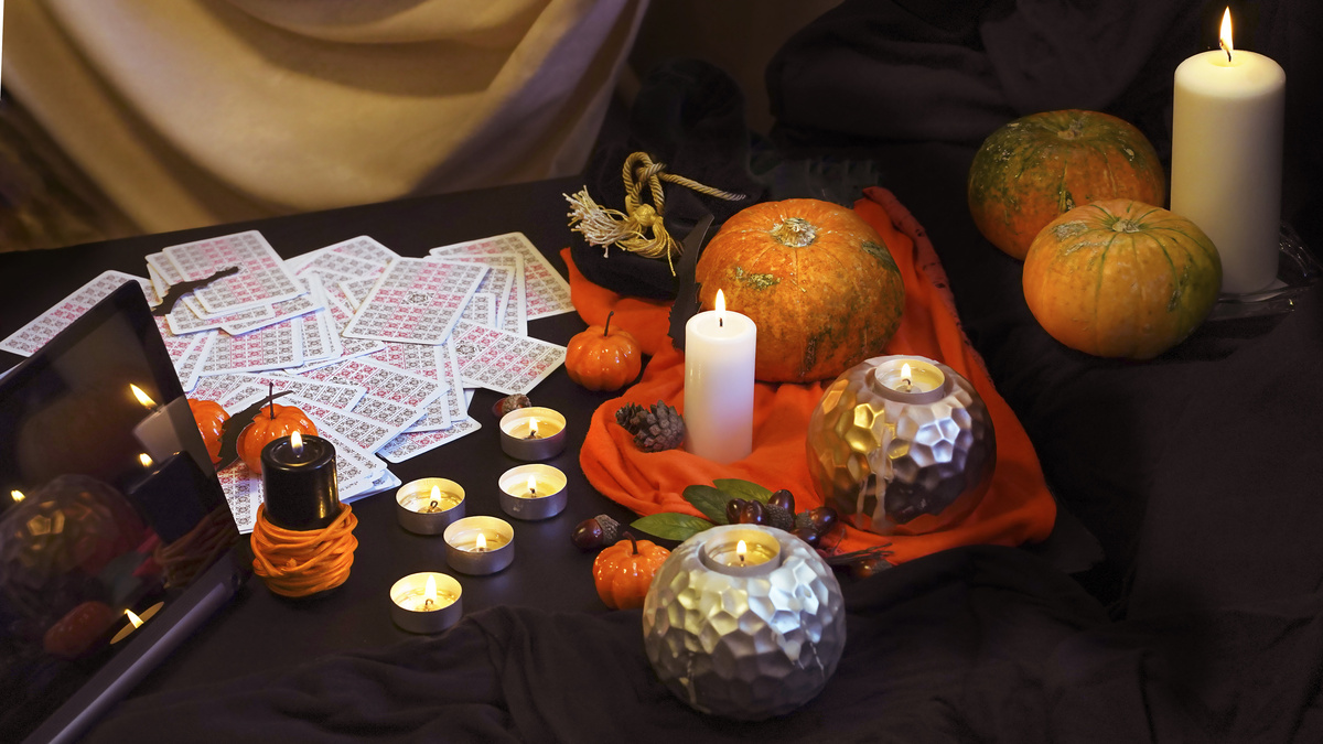 Cartas do Baralho Cigano em mesa com velas e abóboras.