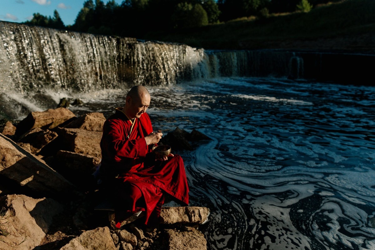 Monge sentado em beira de rio