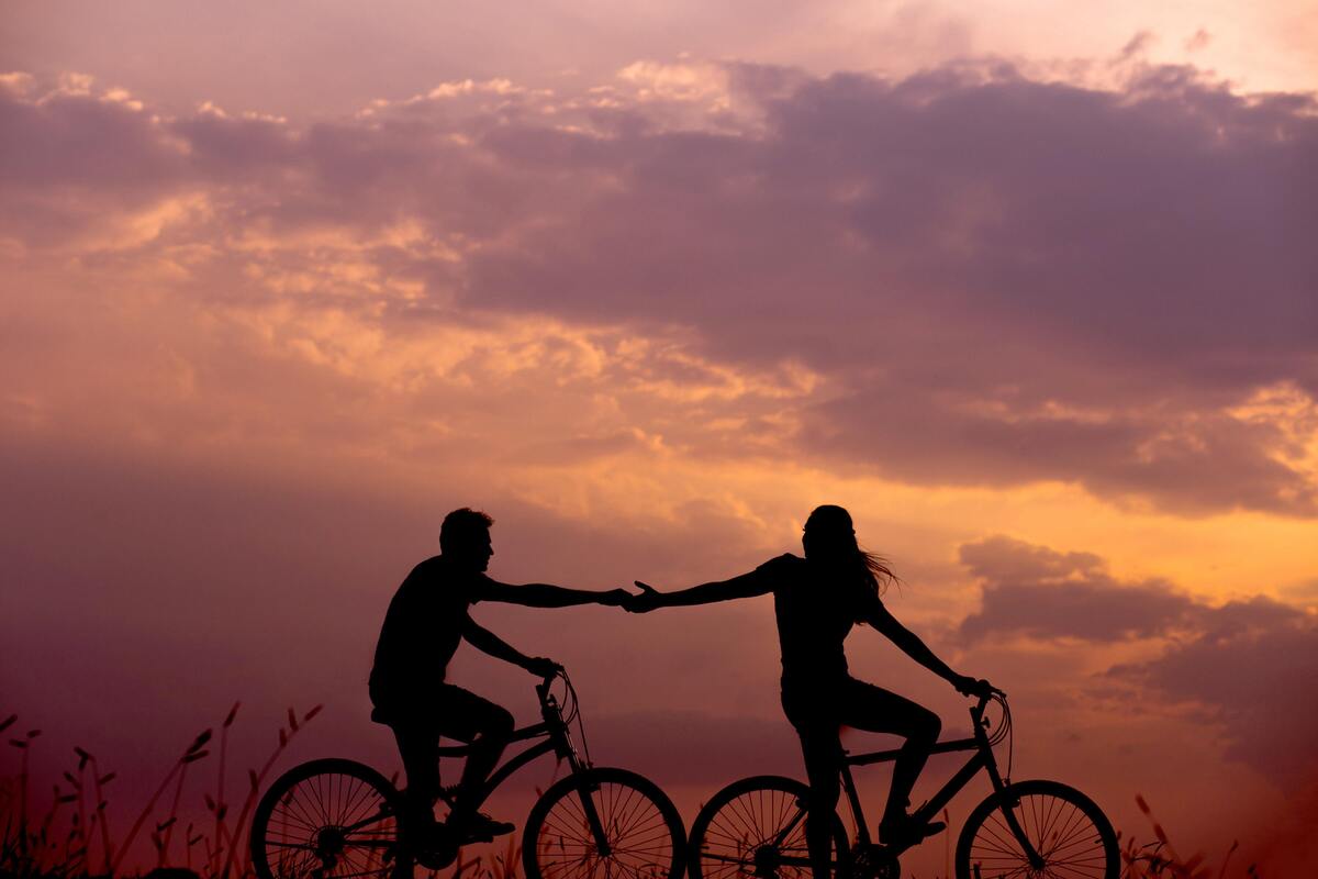 Casal andando de bicicleta ao pôr do sol.