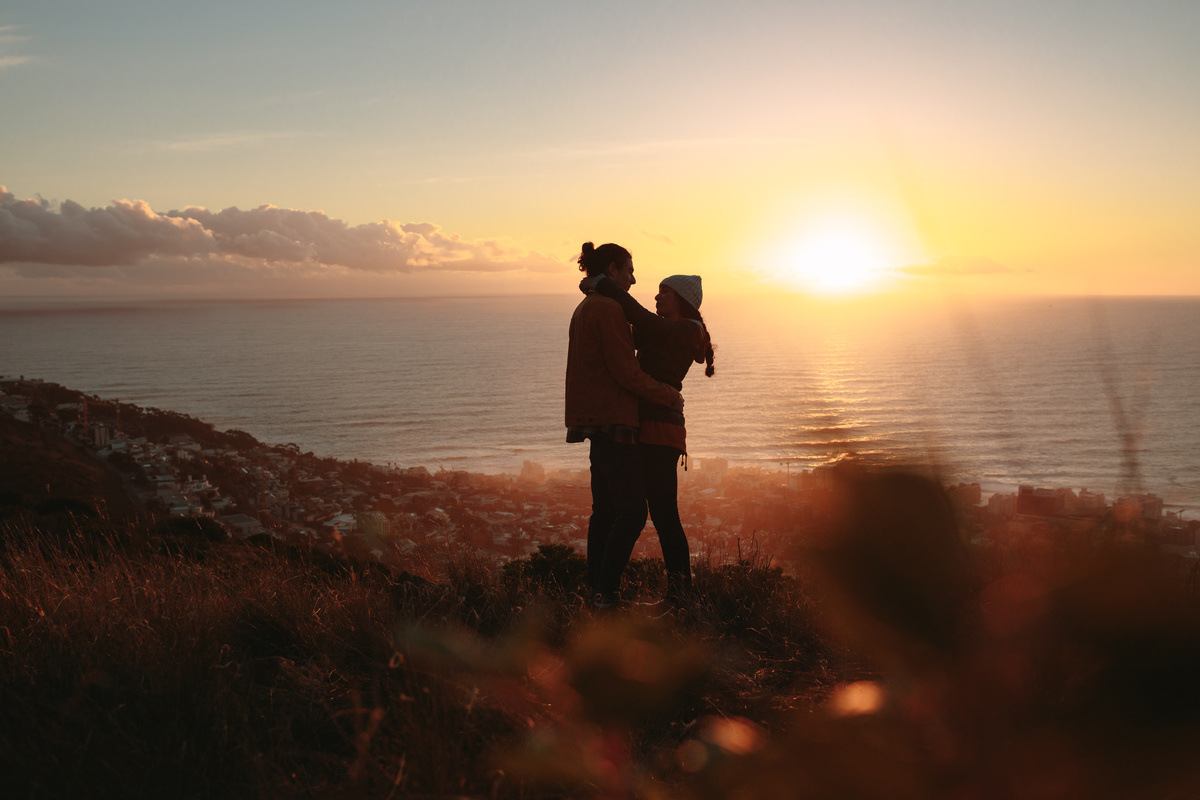 Sombra de casal se abraçando em frente ao por do sol, em paisagem natural e com vista para o mar, representando Virgem e Escorpião.