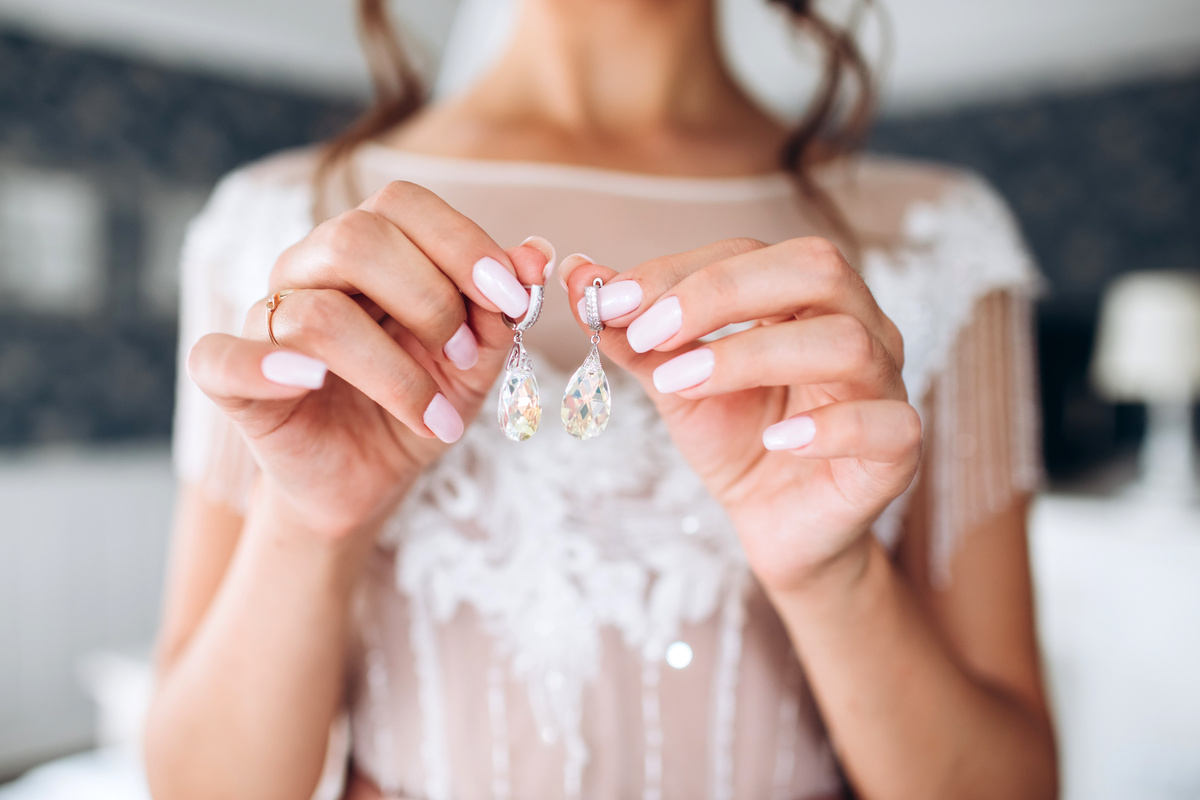 Mulher segurando brincos de cristais com as duas mãos.