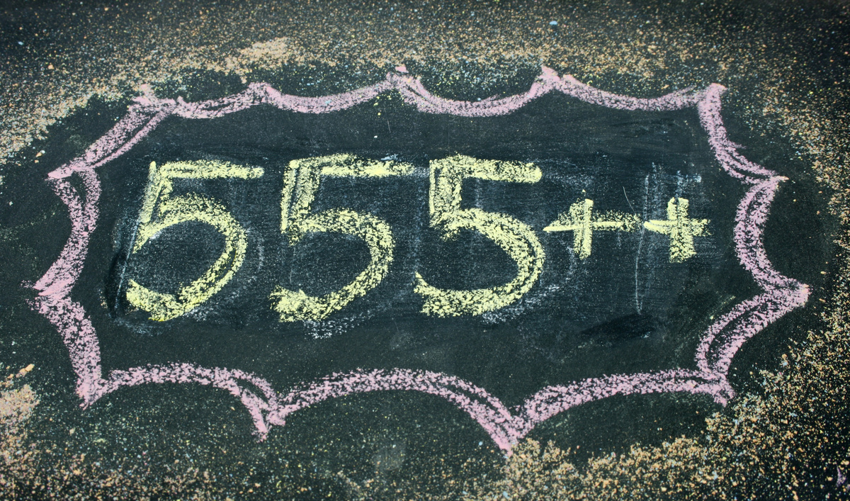 Número 555 escrito em giz colorido no chão, ao lado de dois sinais positivos.