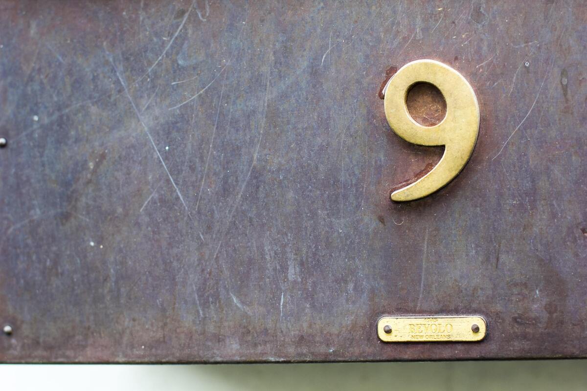Número 9 dourado marcado em superfície de metal marrom.