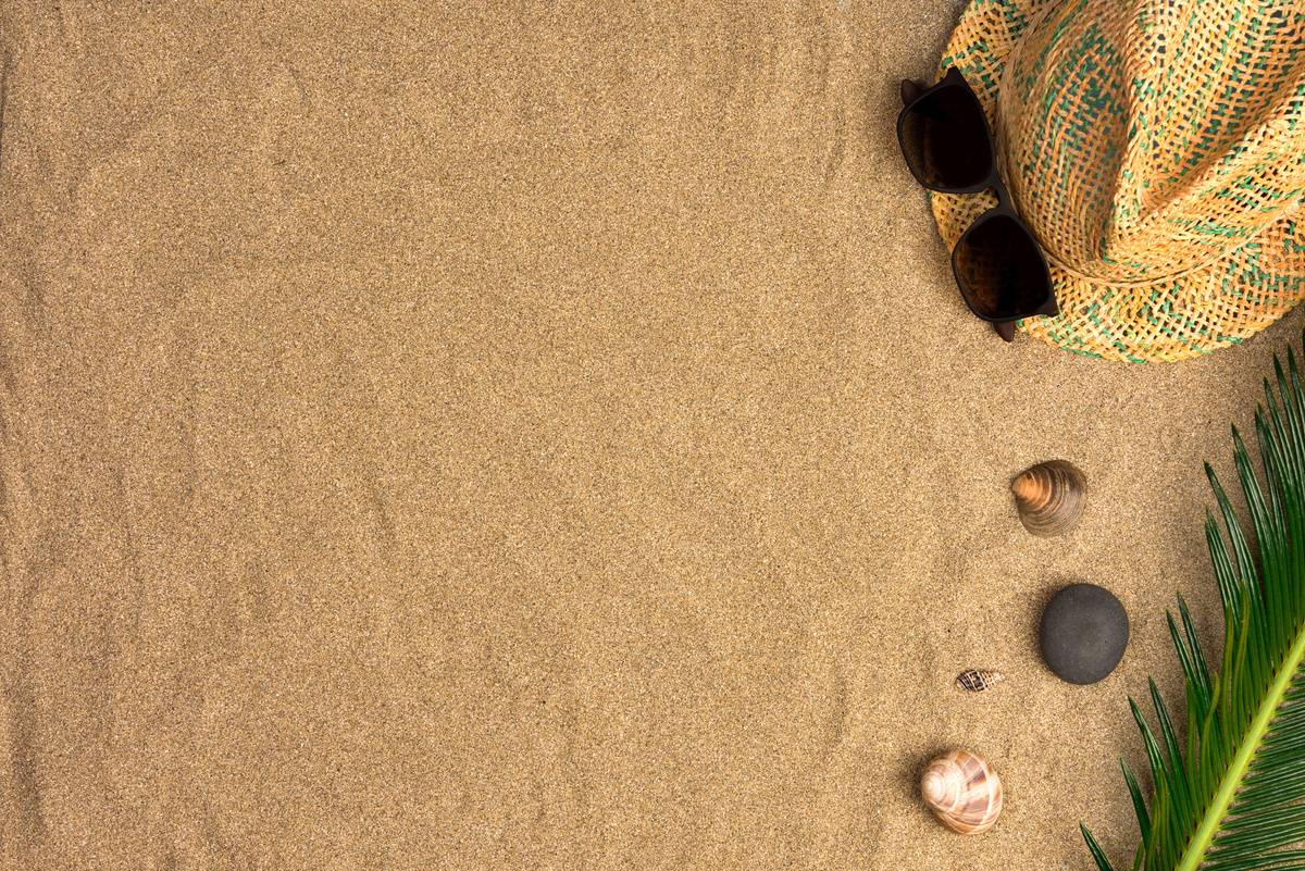 Areia com pedras e chapéu de praia