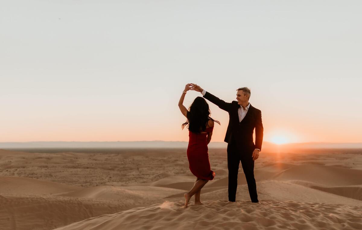Homem e mulher dançando em um campo de areia. 