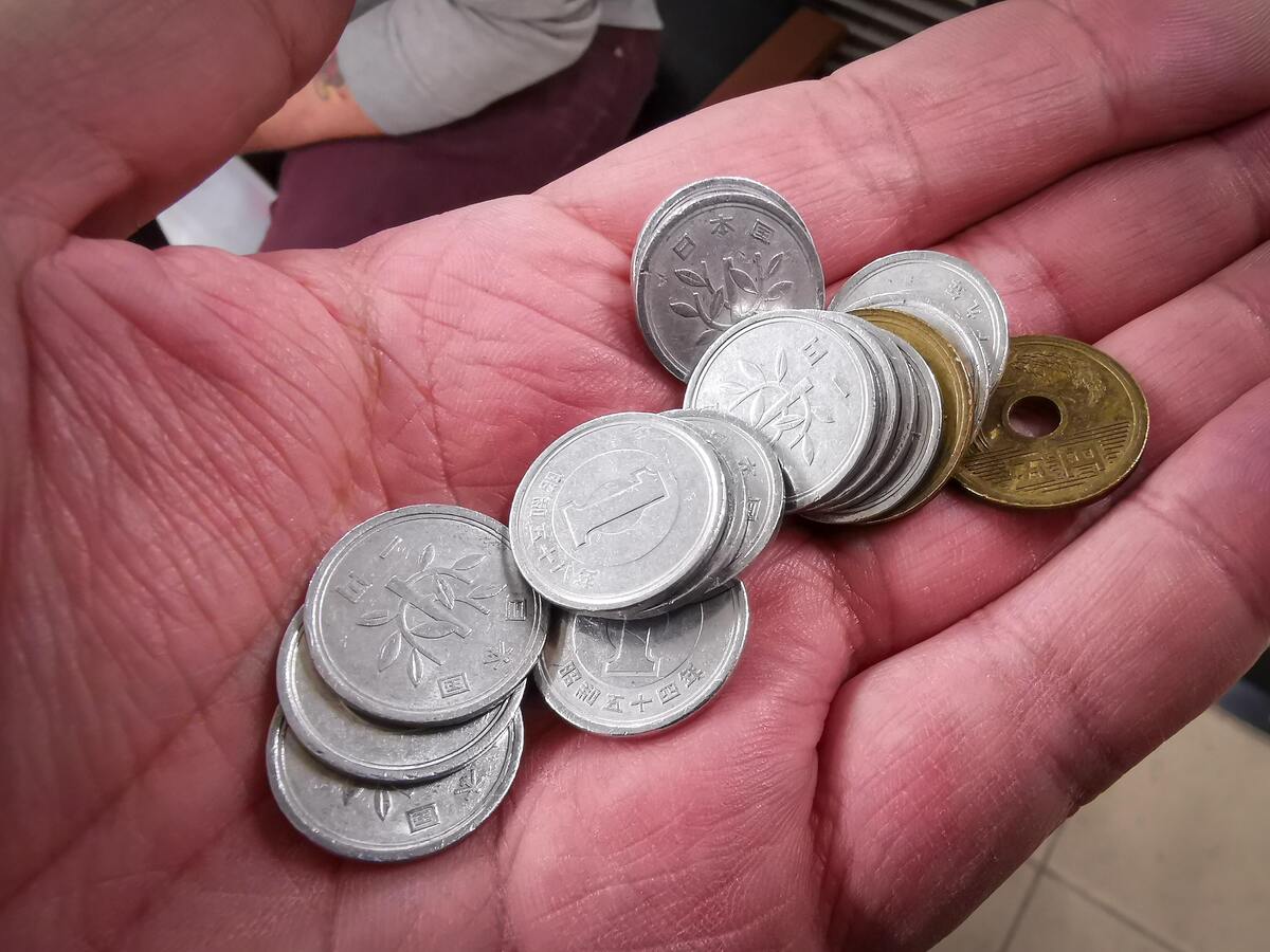Mão aberta com várias moedas.