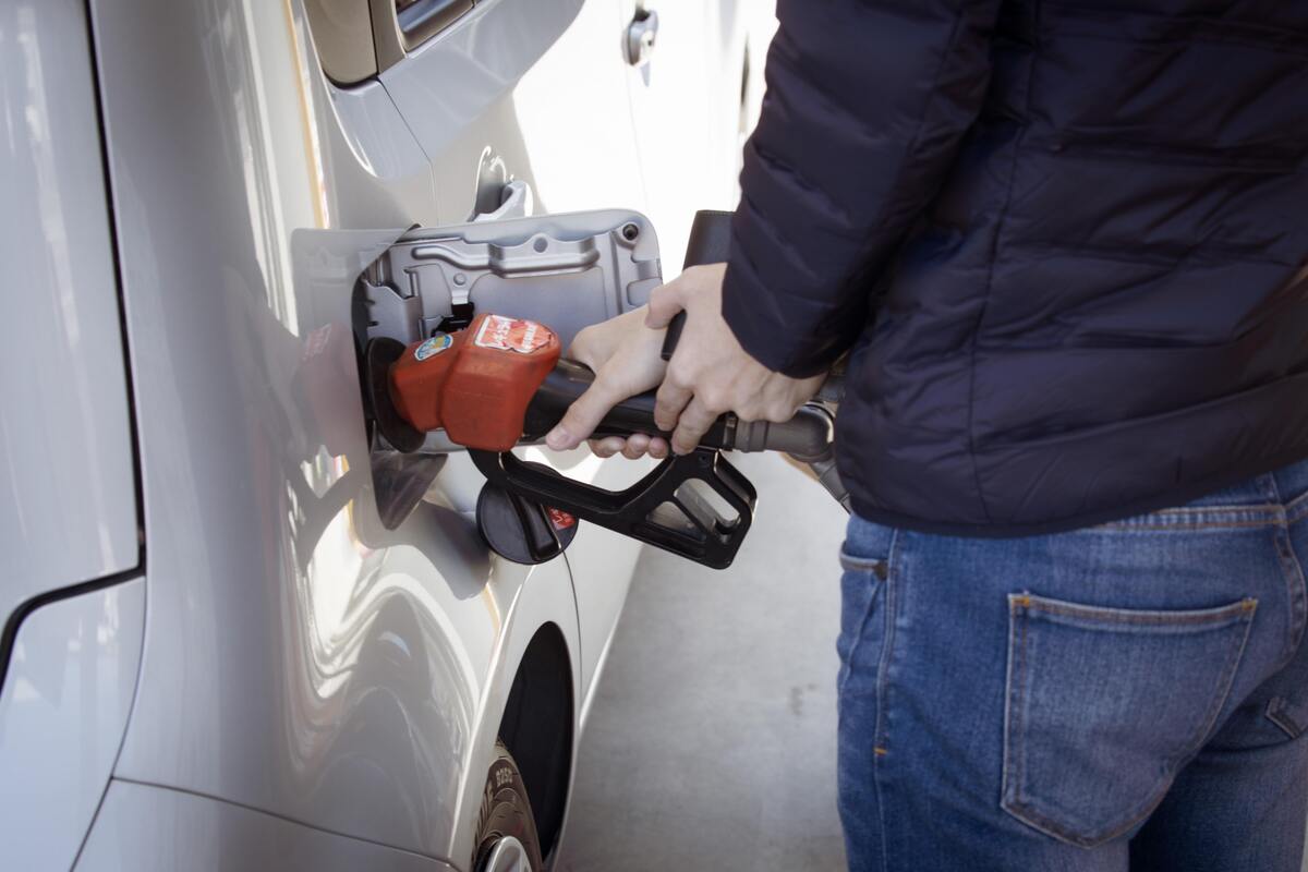 Pessoa abastecendo gasolina do carro em posto de combustível.