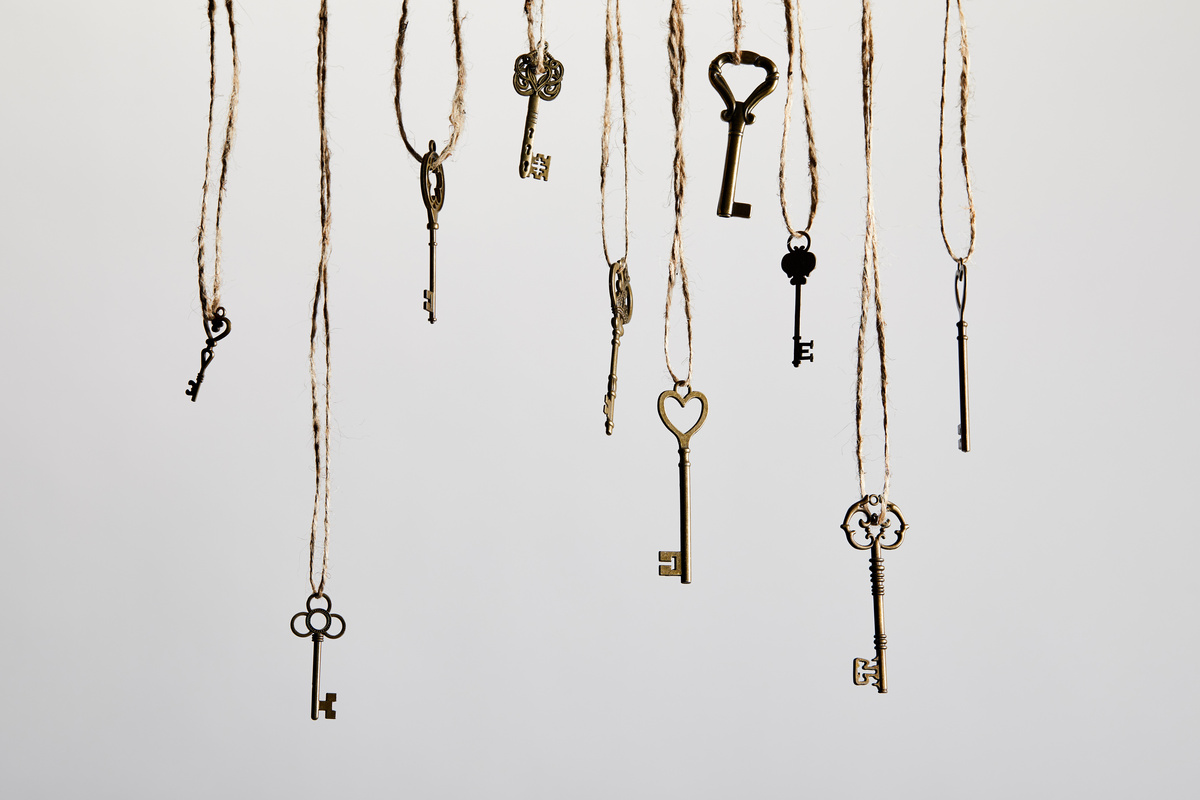 Várias chaves de diversos formatos pendendo do alto, em fundo sombreado.