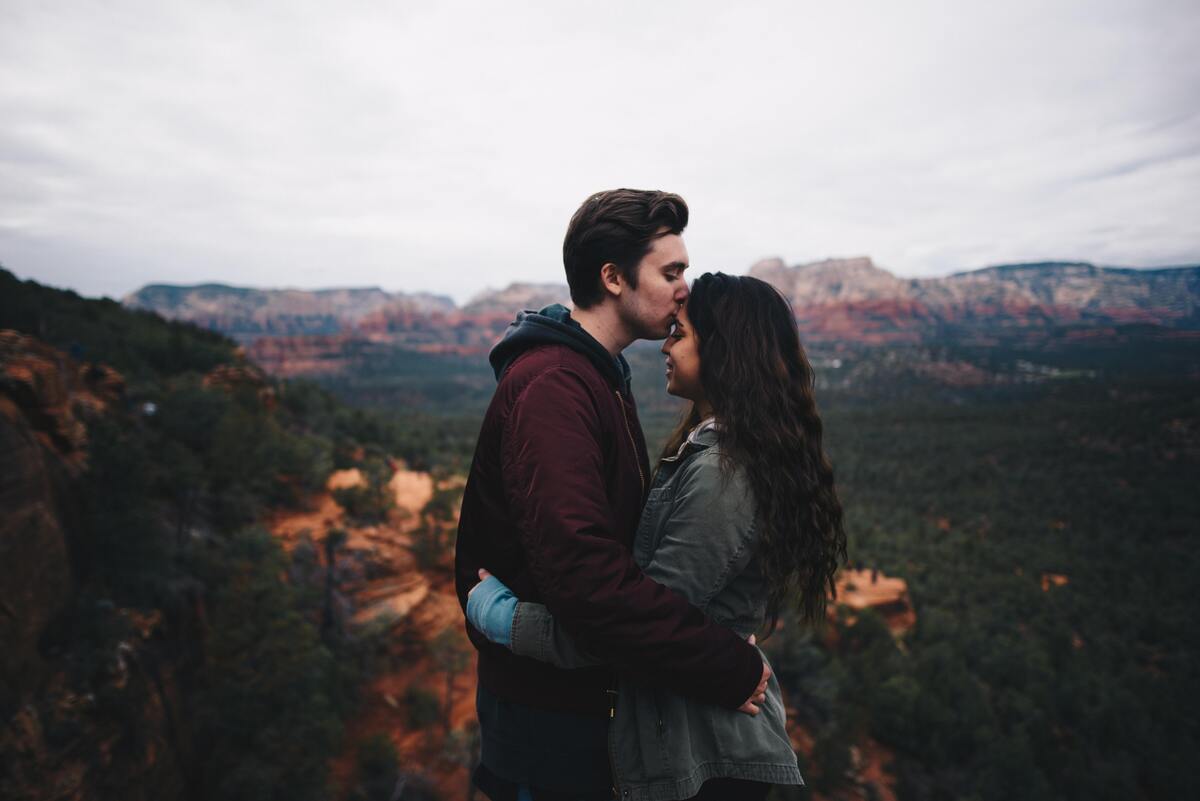Casal abraçado em frente à uma paisagem.