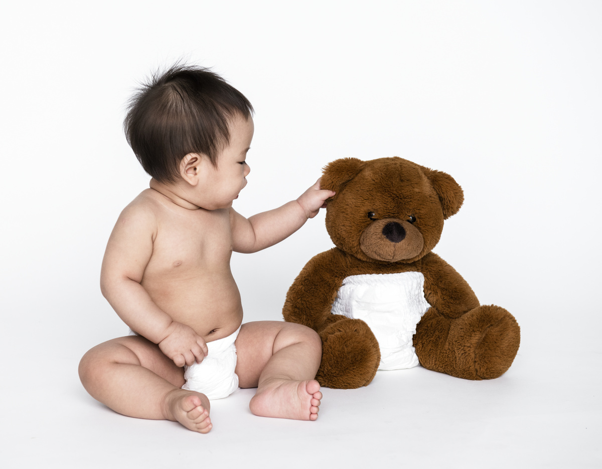 Criança e ursinho de pelúcia usando fraldas.