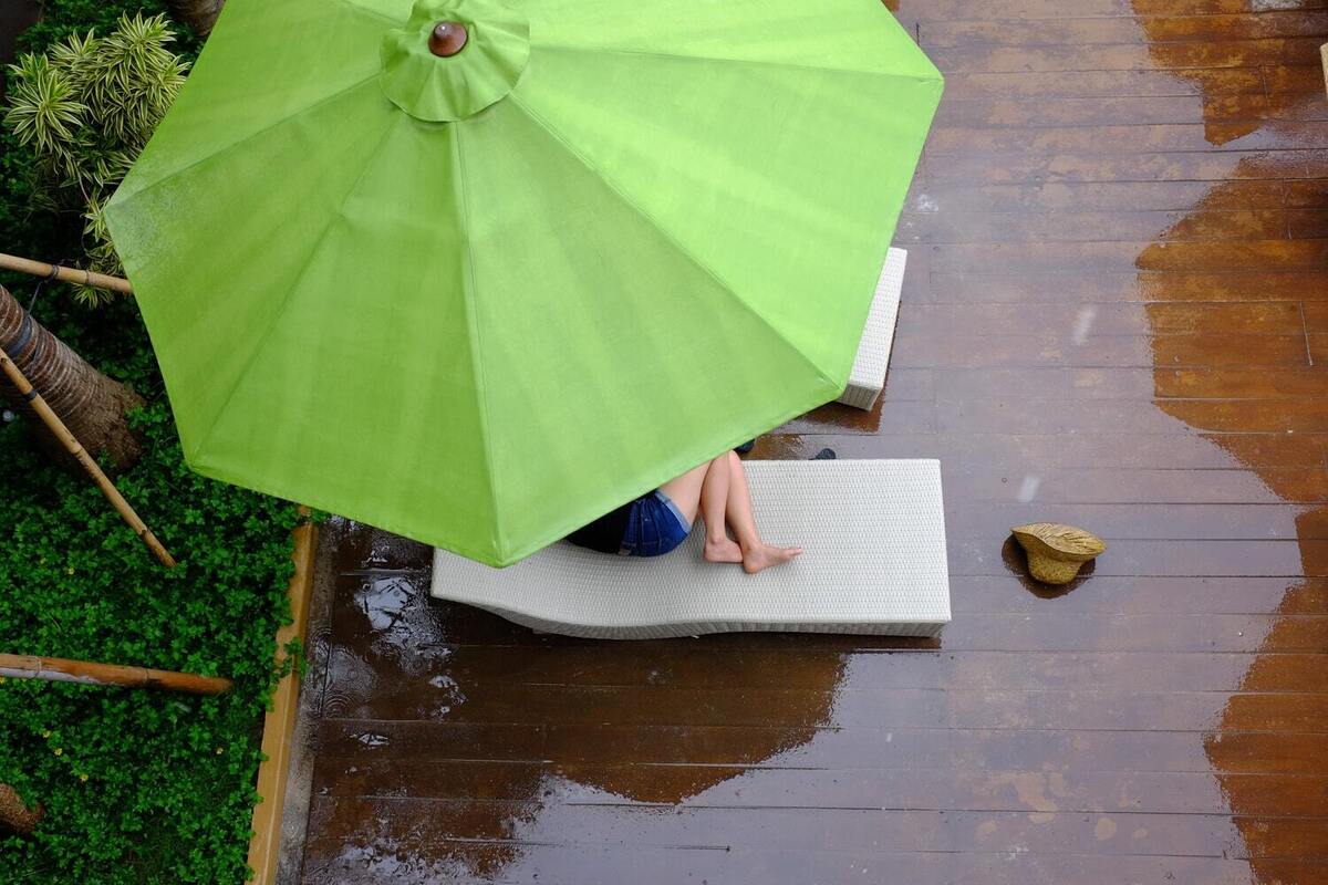 Pessoa se escondendo da chuva em guarda-sol