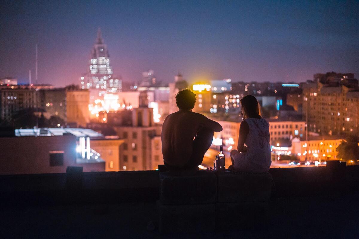 Casal sentado em um terraço observando a cidade.