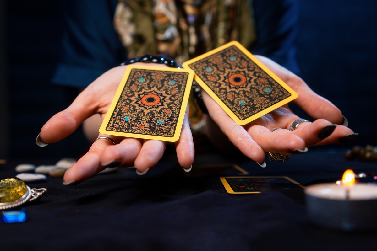 Mulher segurando 2 cartas de Tarot em cada mão.