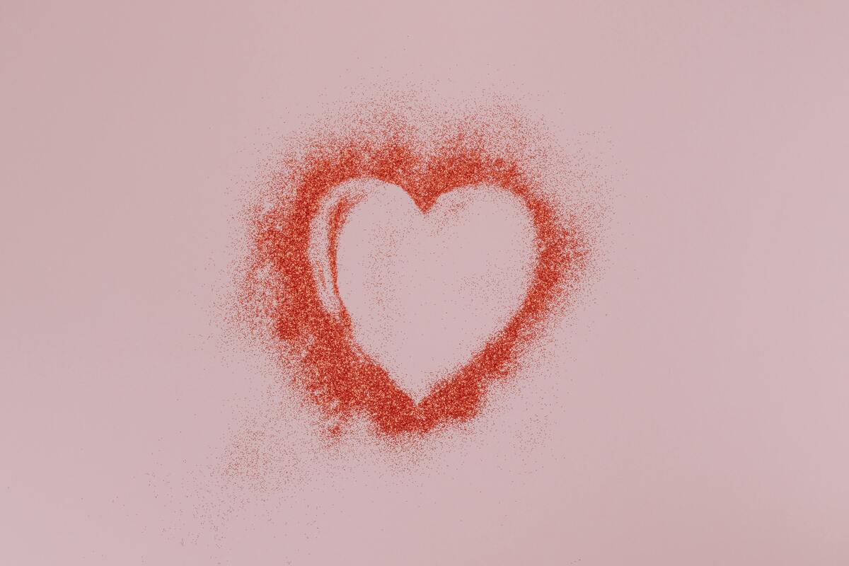 Símbolo de coração vermelho em parede rosa.