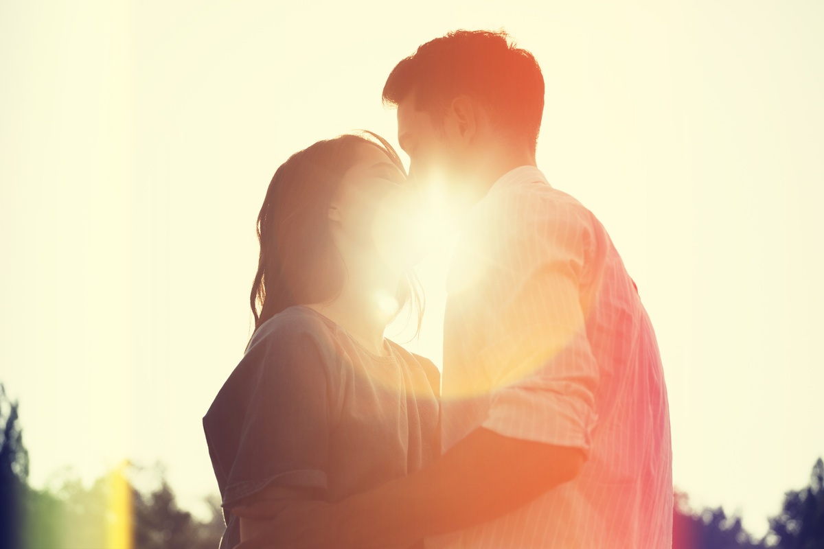 Casal de mulher e homem se beijando à luz do sol.