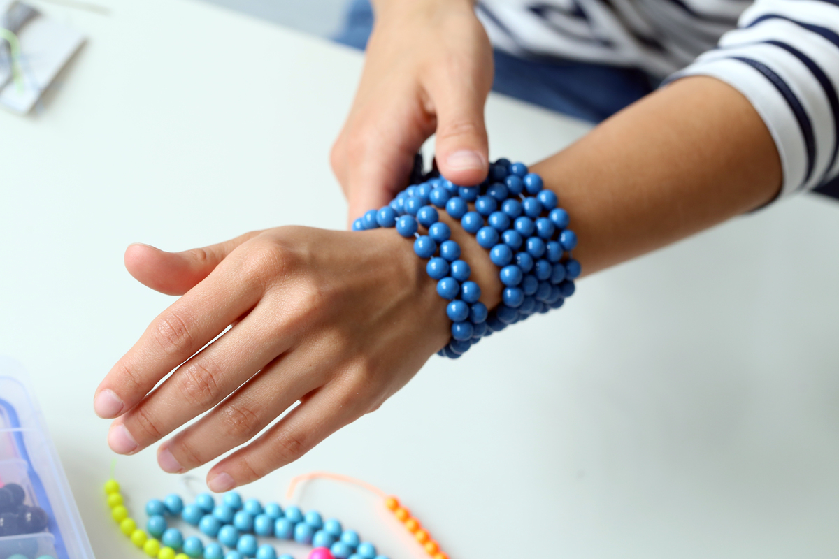 Diversas pulseiras de pedras azuis em volta de um pulso. 