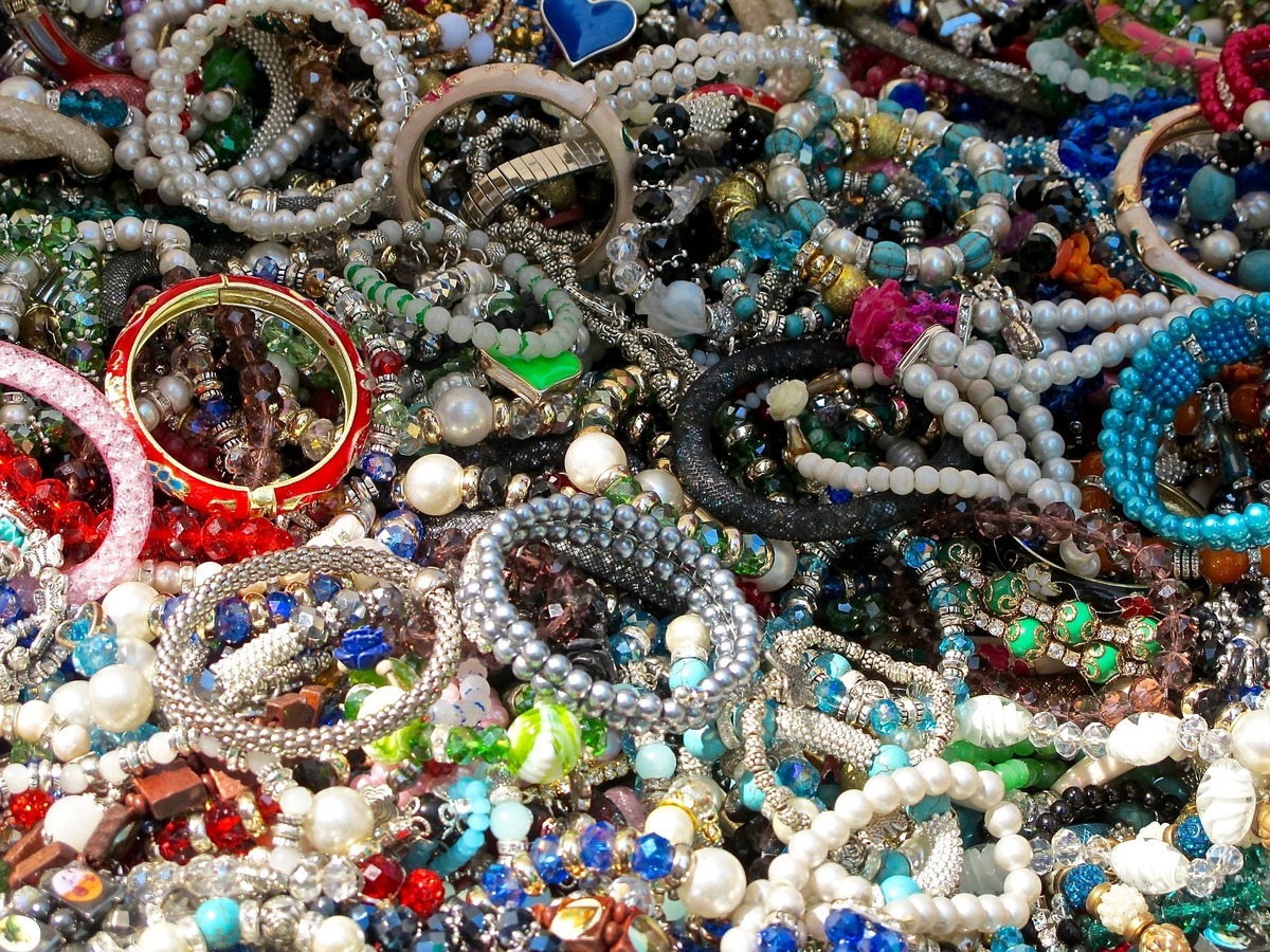 Dezenas de pulseiras de diversos ornamentos espalhadas por superfície. 