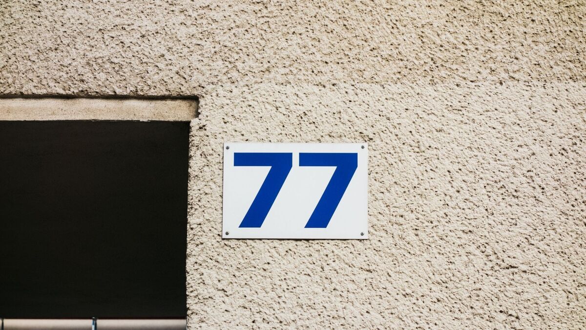Número 77 em parede bege