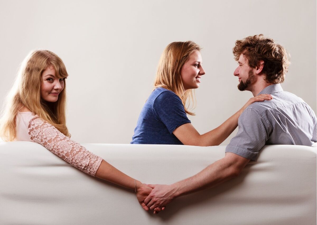 Imagem de homem segurando a mão de outra mulher enquanto conversa com a namorada