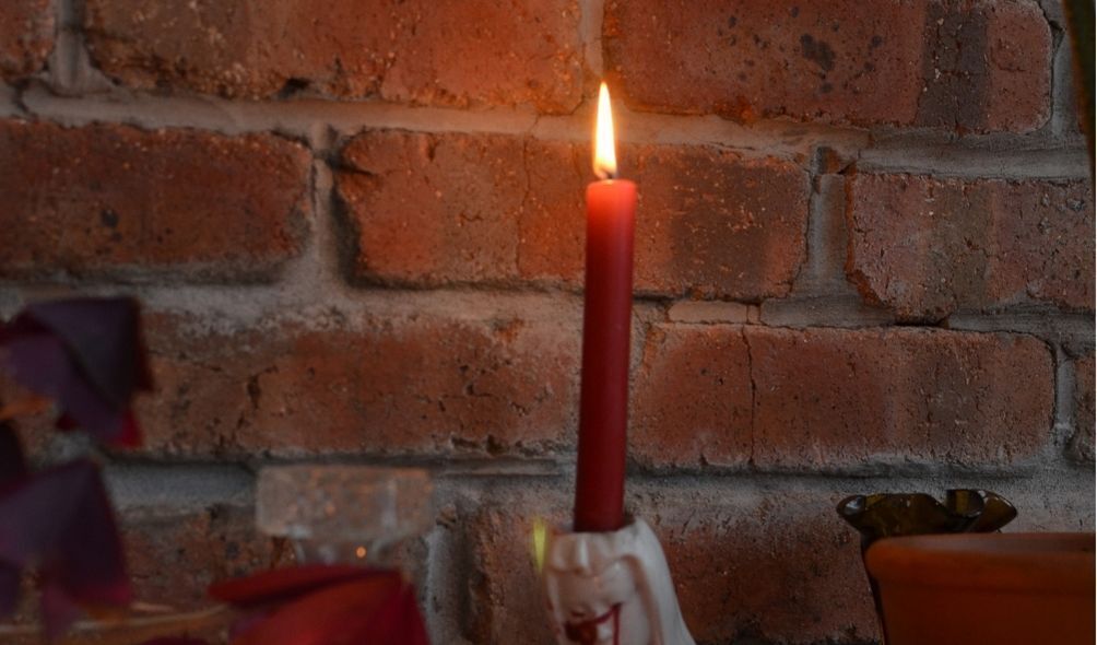 Imagem de vela vermelha em parede de tijolos