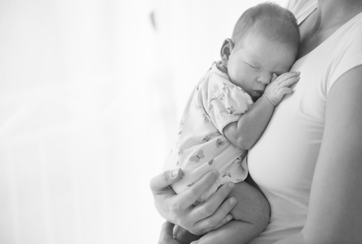 Bebê recém-nascido dormindo no colo da mãe