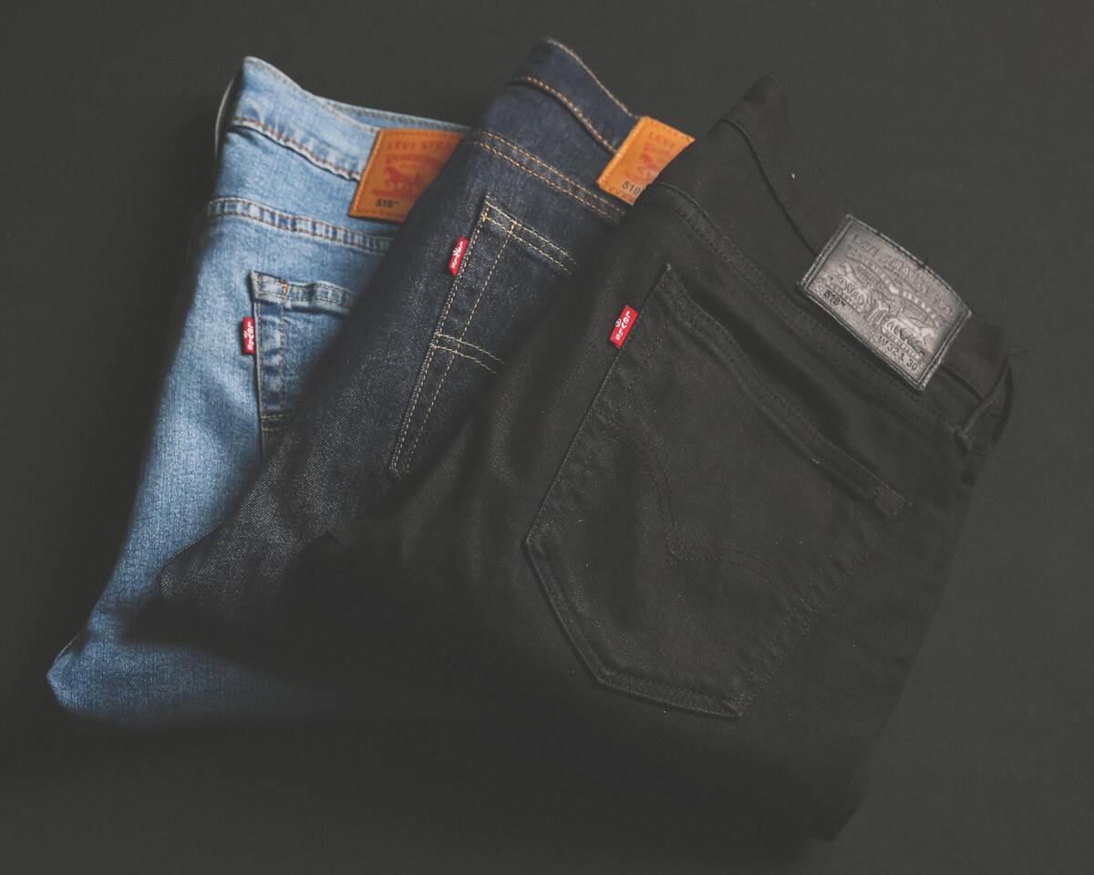 Três tipos de calça jeans dobradas em um fundo preto.