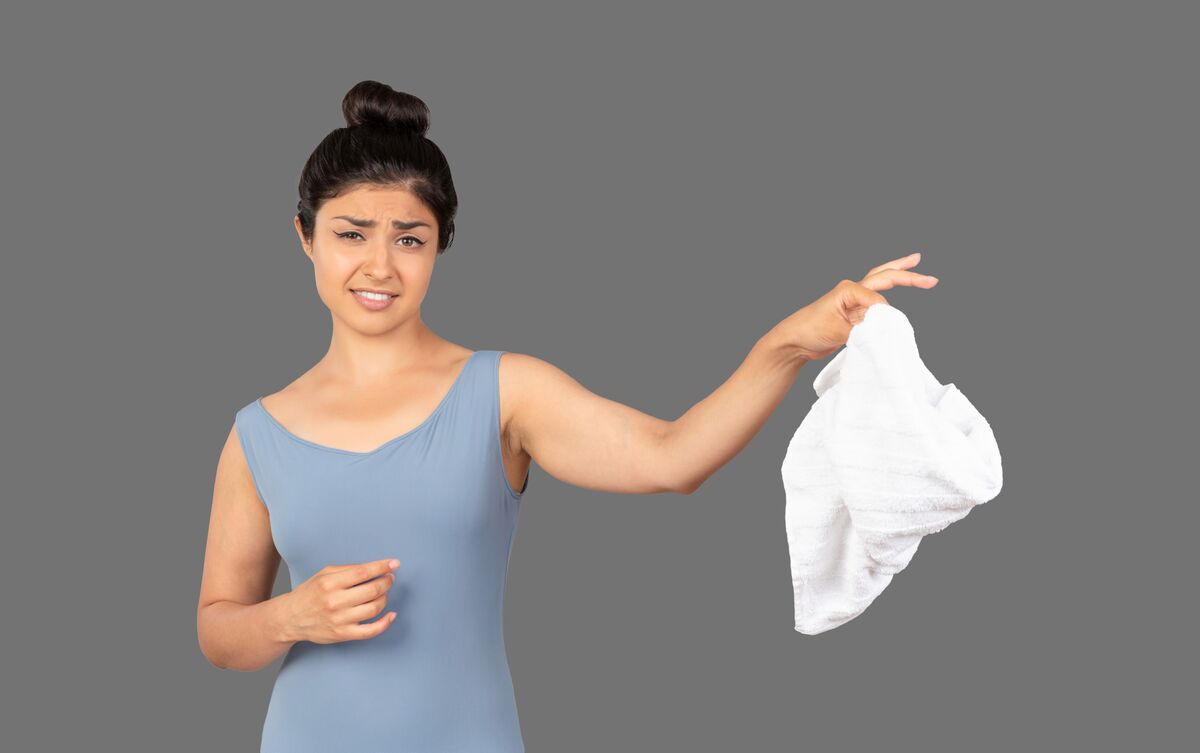 Mulher segurando roupa suja na ponta dos dedos
