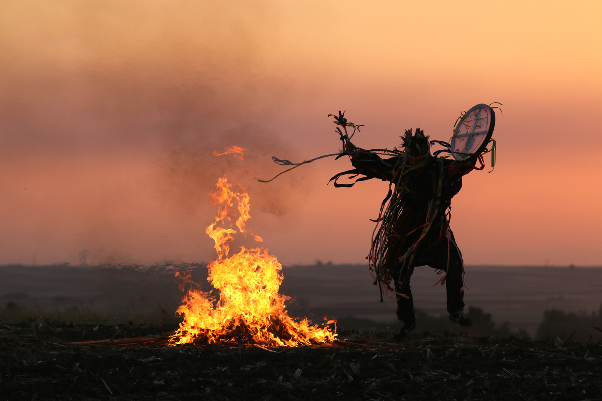 Sombra de Xamã fazendo seu ritual ao lado de fogueira.