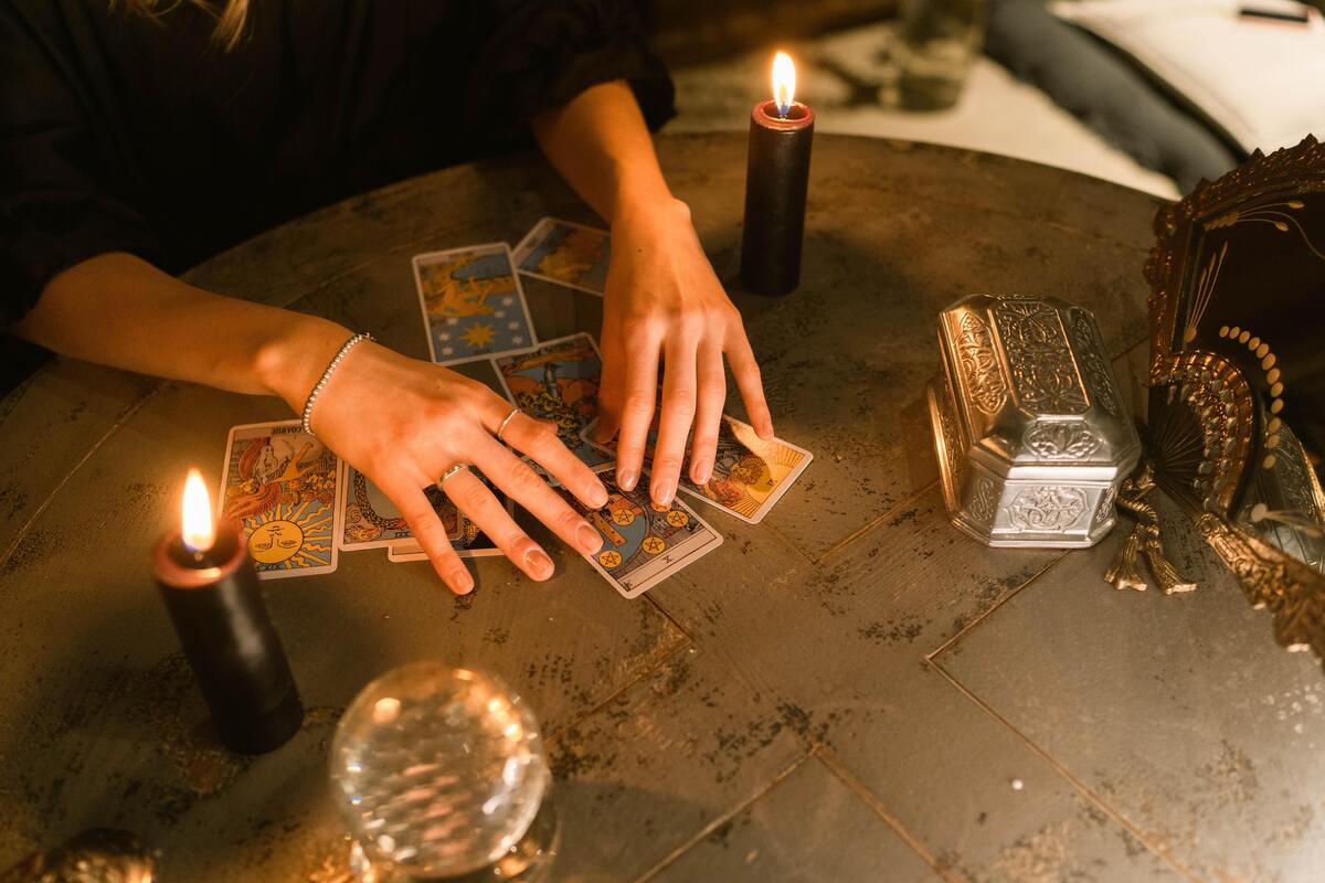 Mãos de uma cartomante mexendo em cartas do tarot