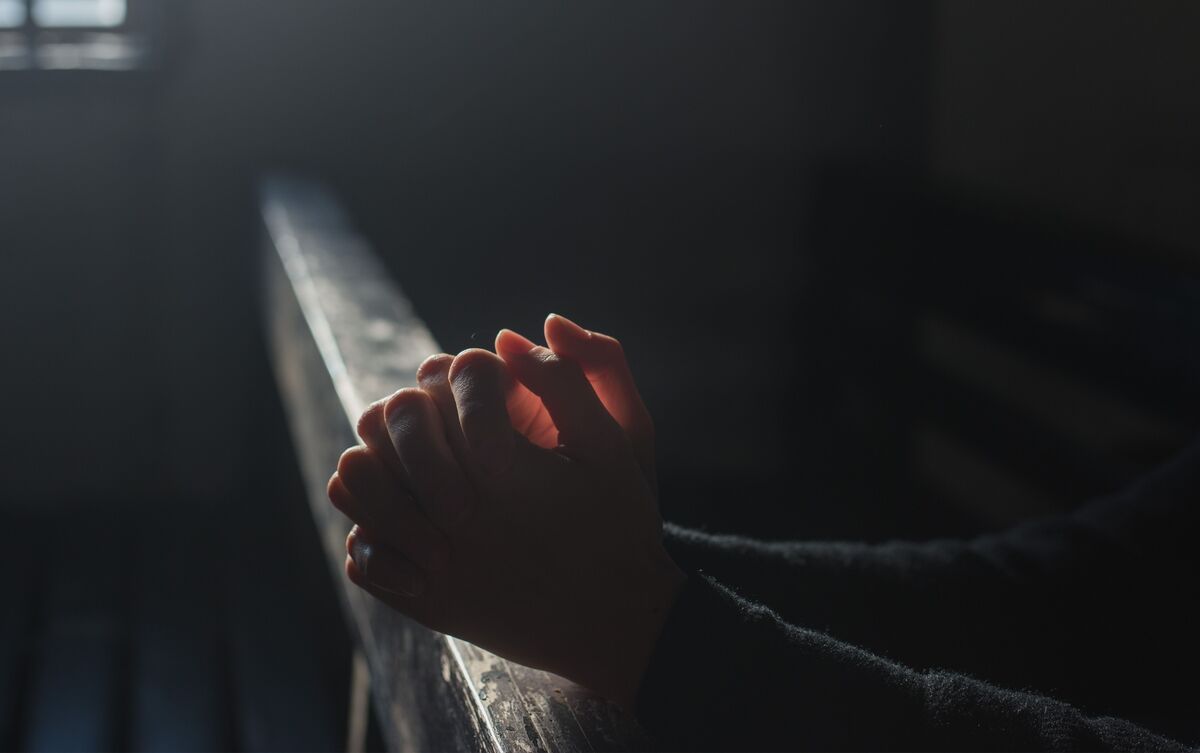 Mulher fazendo oração no escuro.
