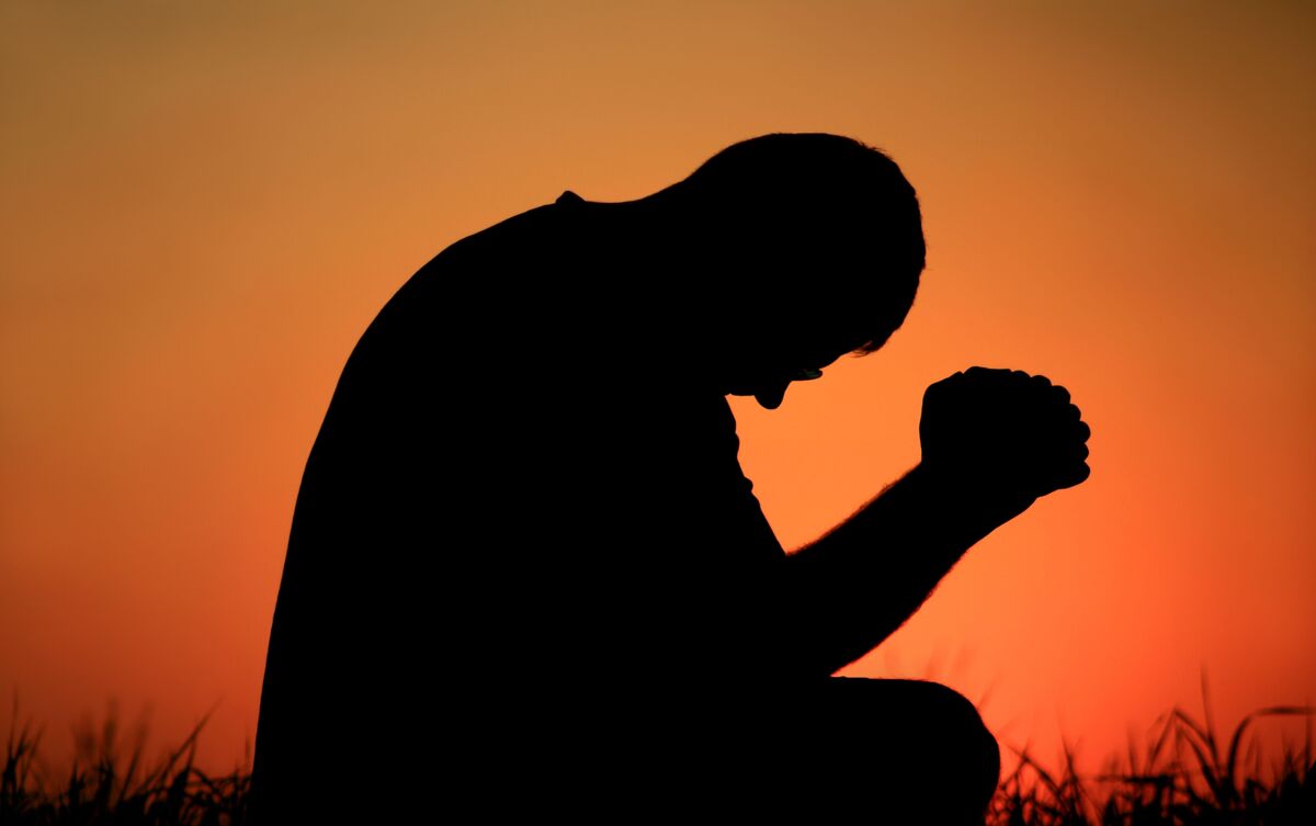 Homem fazendo oração ao pôr do sol.