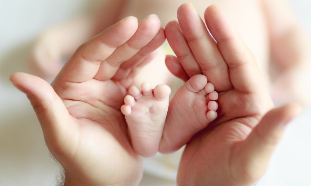 imagem de mãos segurando pés de bebê recém-nascido