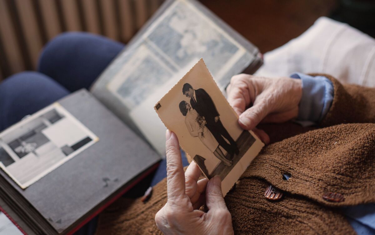 Mulher idosa vendo fotos de marido que já morreu.