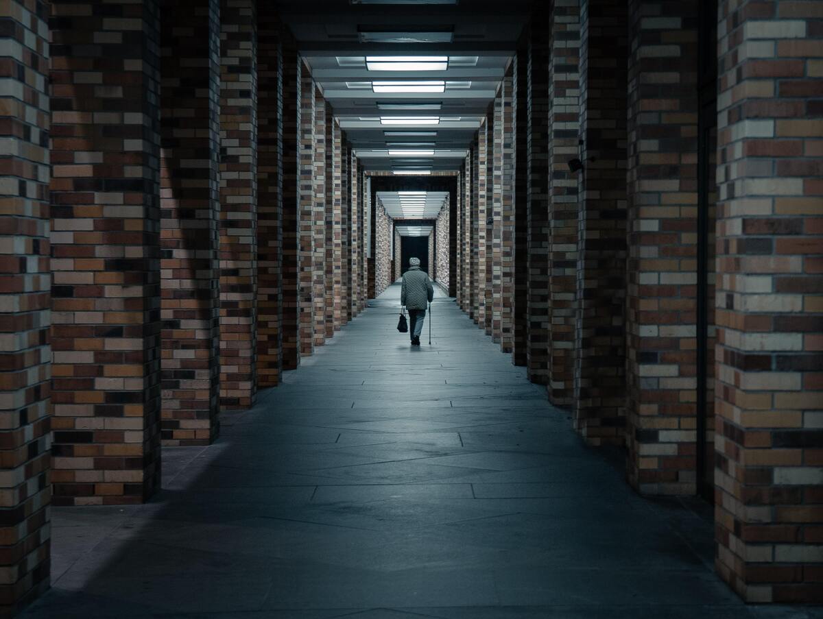 Homem andando sozinho em um corredor.