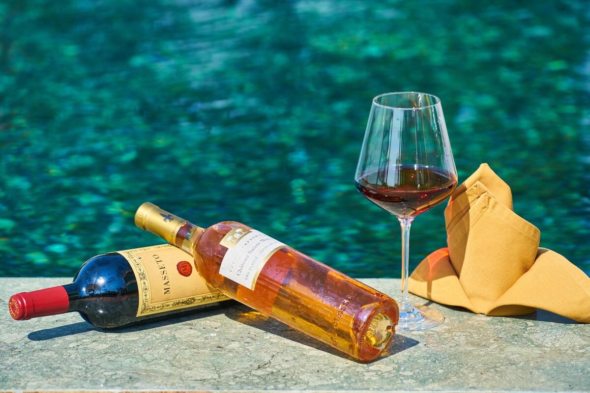 Duas garrafas de vinho, uma taça, um guardanapo em cima de uma pedra