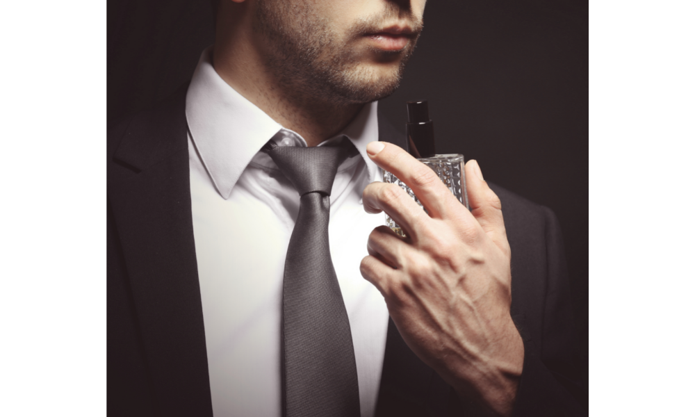 Homem de terno e gravata segurando um perfume.
