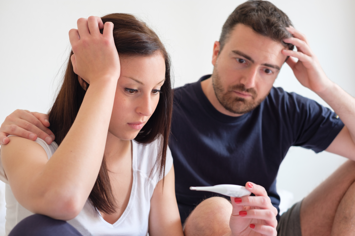 Casal olhando preocupados um exame de gravidez positivo