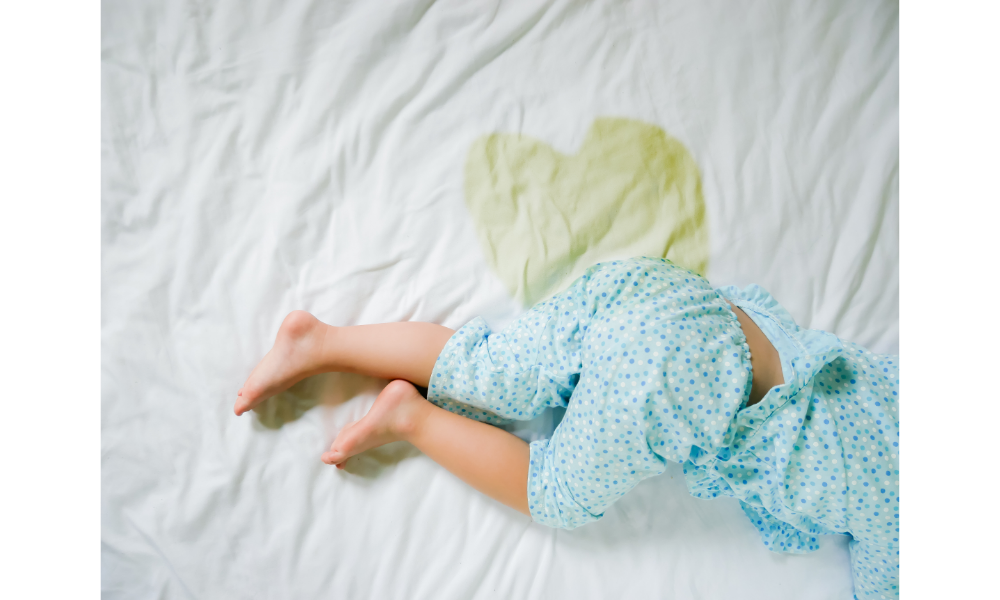 Criança em uma cama com marca de molhada por xixi.