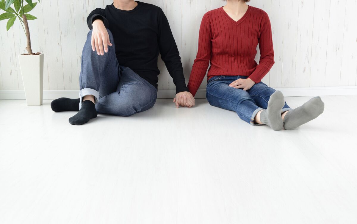 Homem e mulher sentados no chão e de mãos dadas.