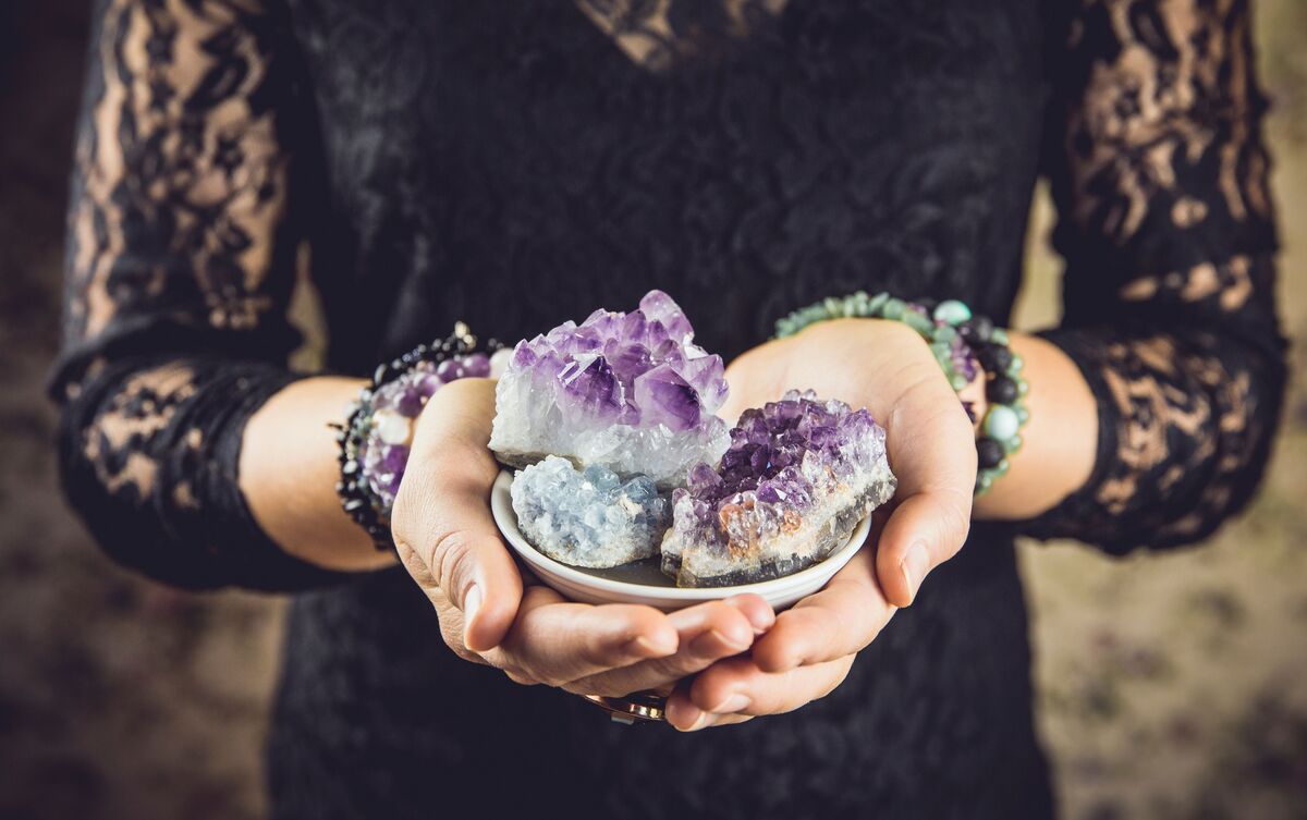 Mulher segurando pedras e cristais variados nas mãos.