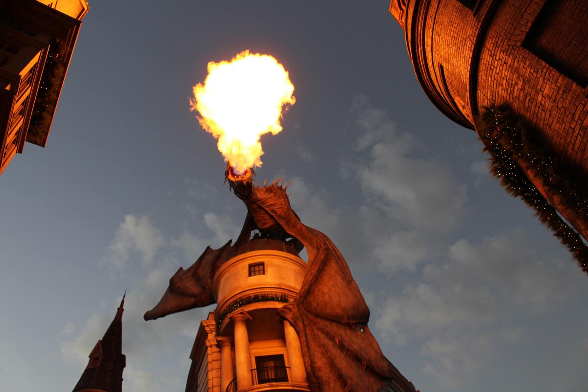 Estátua de um dragão em cima de um prédio, soltando fogo.