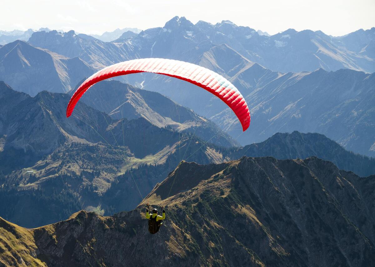 Pessoa voando de paraquedas entre montanhas