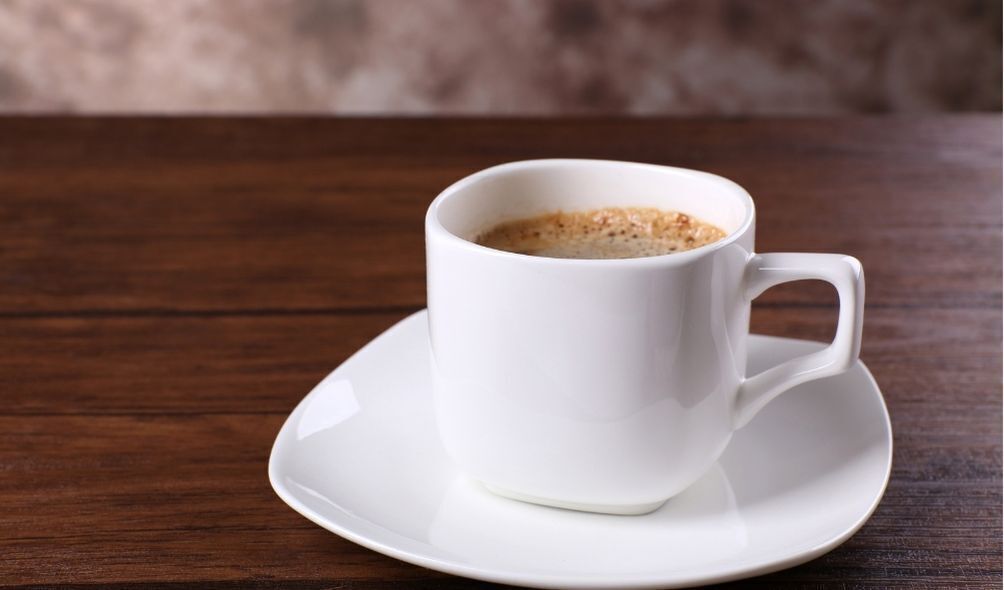 Xícara branca de café em cima de mesa de madeira