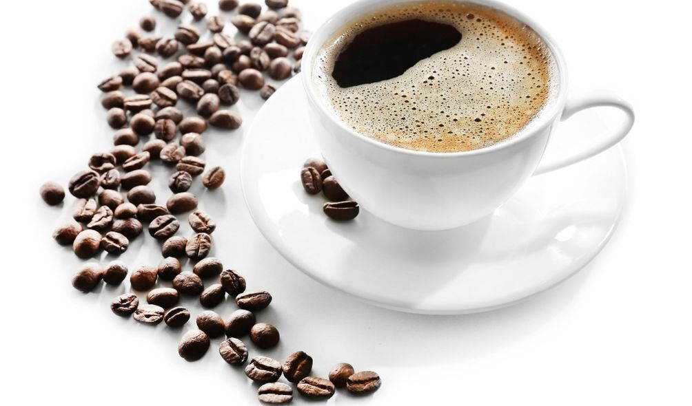 Xícara branca de café com grãos de café ao lado